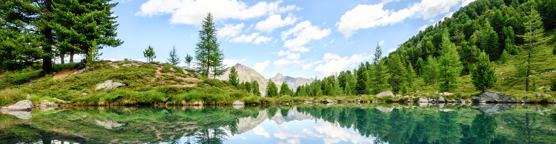 Idyllischer Bergsee in Ischgl unter klarem Himmel.